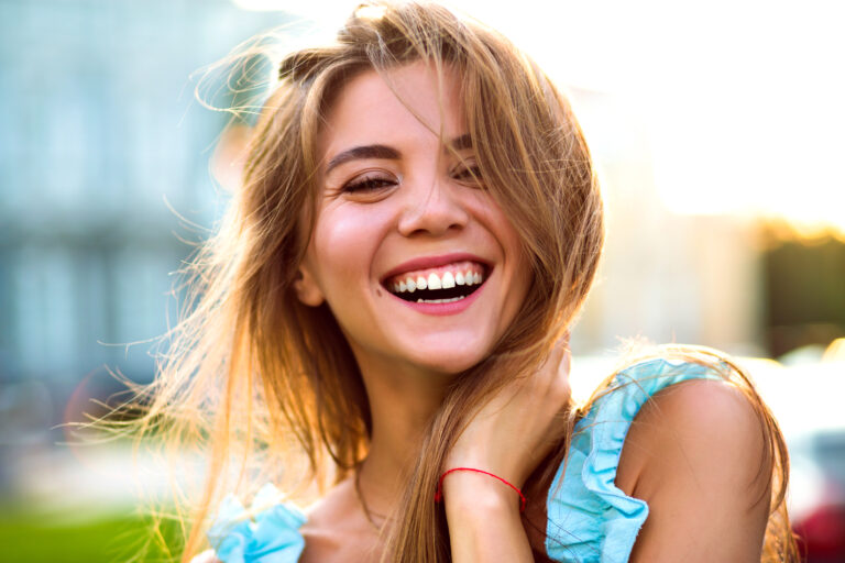 Close up sunny portrait of beautiful magnificent woman with natural make up and big amazing smile looking on camera, bright sunlight , positive mood.